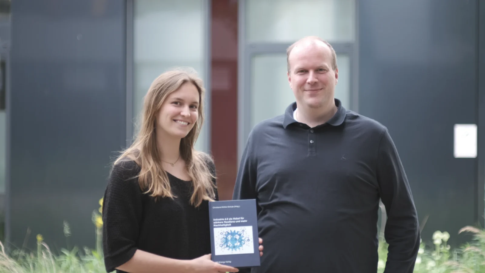 Zwei Mitarbeitende mit Buch in Hand